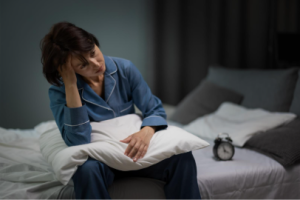 Exhausted woman with PCOS sitting in bed tired