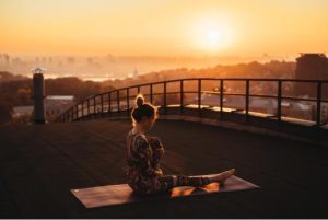 Woman practicing yoga at sunrise for PCOS stress management