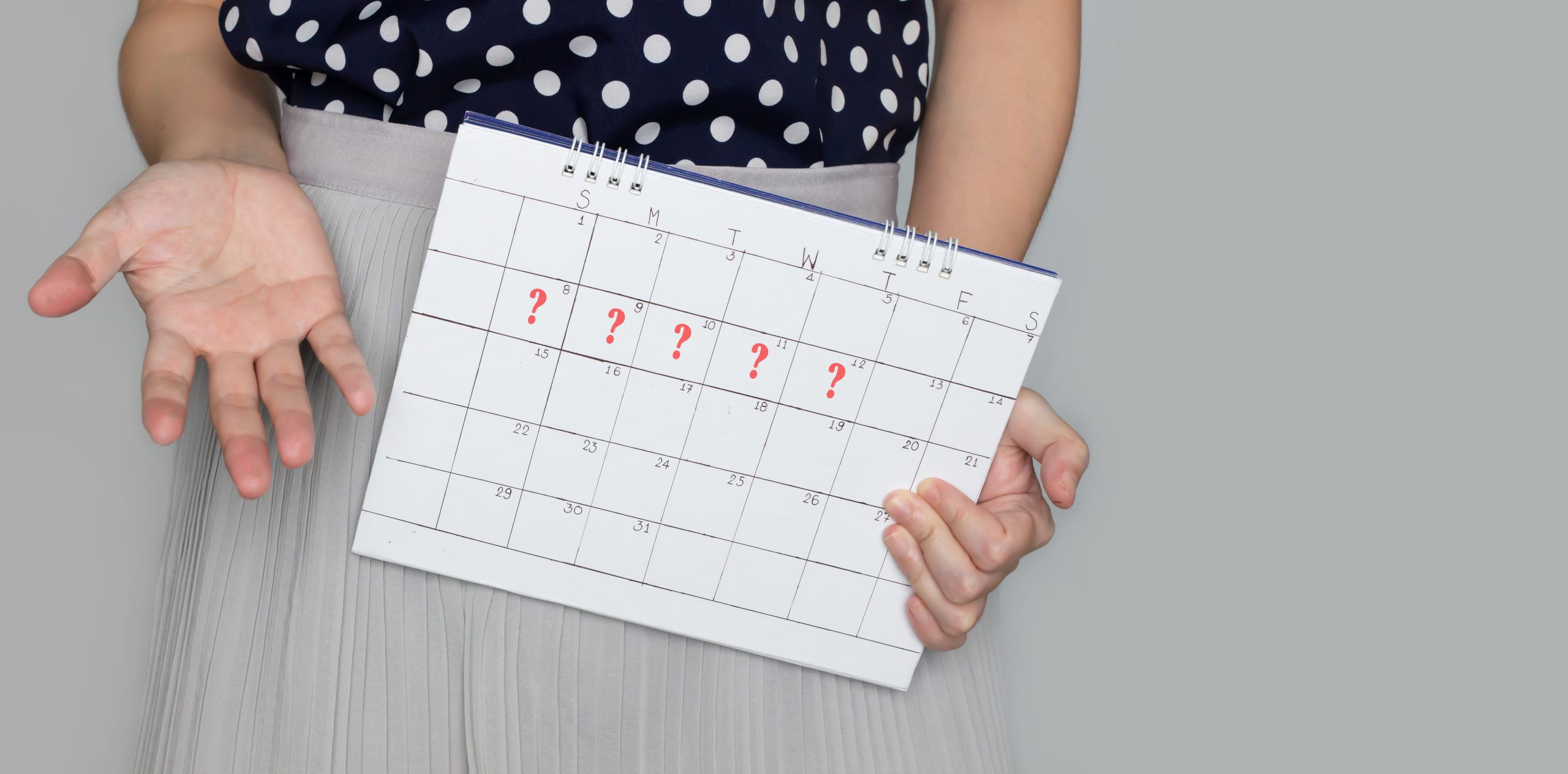 Woman holding a calendar with question marks, showing irregular periods and missed cycle dates linked to PCOS.