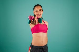 Woman holding dumbbells and smiling, showing exercise for PCOS weight loss and improved insulin resistance. 